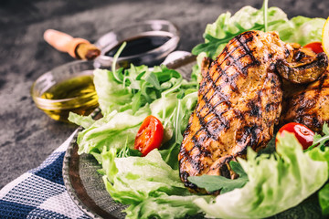 Grilled chicken breast in different variations with lettuce salad cherry tomatoes .mushrooms herbs cut lemon on a wooden board or teflon pan. Traditional cuisine. Grill kitchen.
