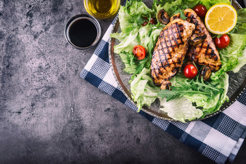Grilled chicken breast in different variations with lettuce salad cherry tomatoes .mushrooms herbs cut lemon on a wooden board or teflon pan. Traditional cuisine. Grill kitchen.