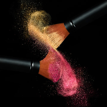 Makeup brushes applying powder isolated on black
