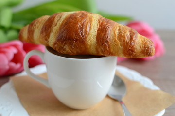 cup of cappuccino and yummy croissant with flowers