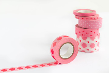 Pink washi tape rolls in pile, white background.