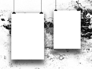Close-up of two asymmetrical blank frames hanged by clips against black and white scratched wall...