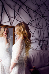 the beautiful girl in a long white dress looking into mirror.