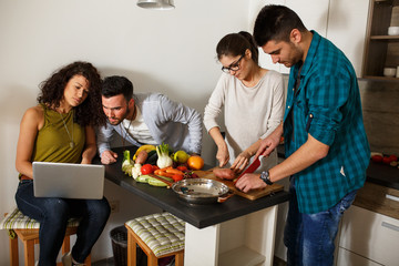 Young group of friends preparing vegetable meal and making fun.