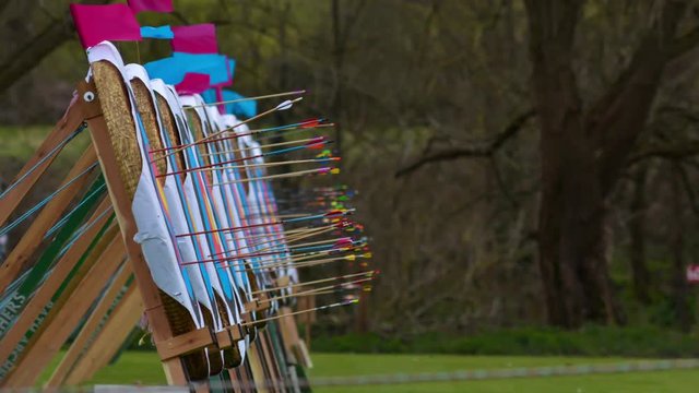 Arrows landing in row of archery targets. Arrows fly towards and stick into multiple targets in a bow and arrow competition held in windy conditions, shown sped up as a time-lapse 
