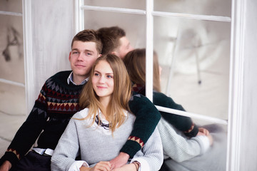 Couple of teenagers sitting against mirror wall