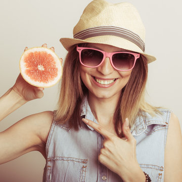 Happy woman in hat and sunglasses with grapefruit.