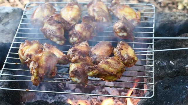 Chicken wings and legs cooking on a barbecue grill, closeup. Outdoor cooking.