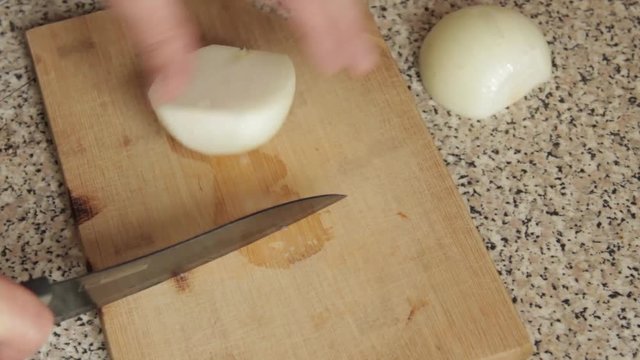 Повар разрезает репчатый лук на две части  Cook cuts the onion into two parts 