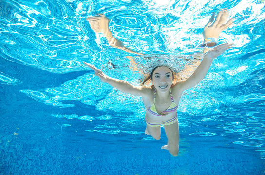 Child swims in pool underwater, girl has fun under water, active kid sport on family vacation
