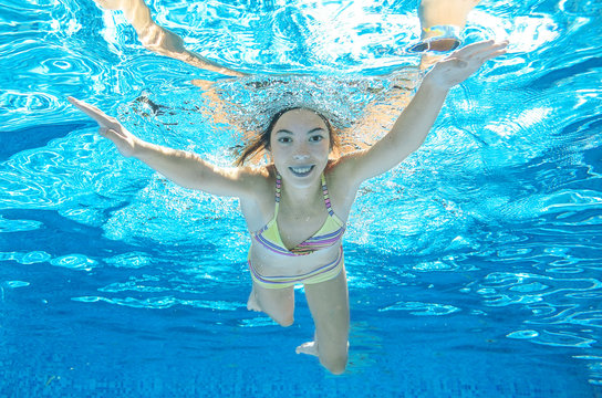 Child swims in pool underwater, happy active girl dives and has fun under water, kid sport on family vacation
