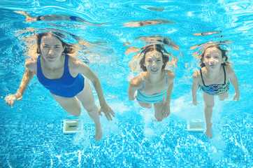 Obraz na płótnie Canvas Family swims in pool under water, happy active mother and children have fun underwater, kids sport on family vacation 