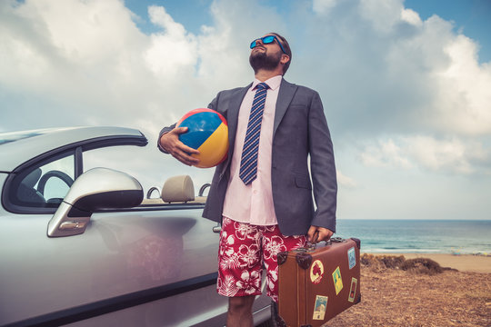 Businessman standing on a beach near car