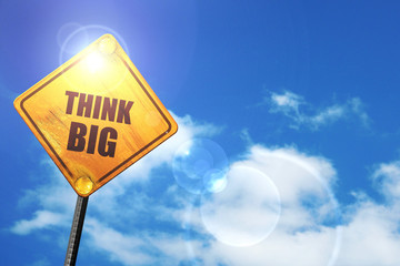 Yellow road sign with a blue sky and white clouds: think big