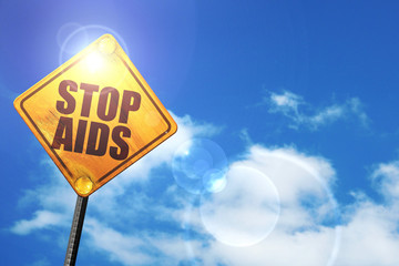 Yellow road sign with a blue sky and white clouds: stop aids