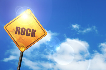 Yellow road sign with a blue sky and white clouds: rock music
