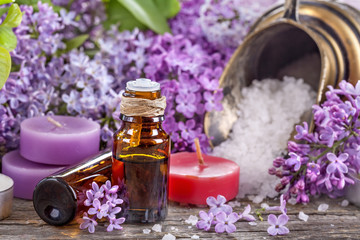 Fototapeta na wymiar Essential oils and bath salt with a background of lilac