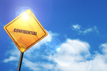 Yellow road sign with a blue sky and white clouds: confidential 