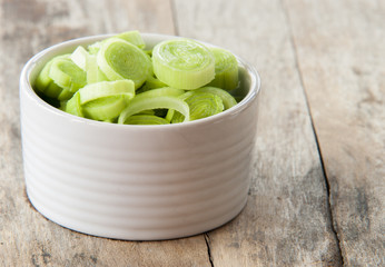 fresh raw leek slice in a bowl in wooden background