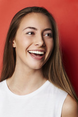 Beautiful young woman smiling against red background
