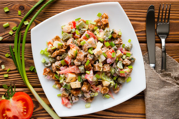 salad in a white plate next to the cutlery, green onions and half of tomato
