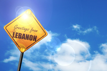 Yellow road sign with a blue sky and white clouds: Greetings fro