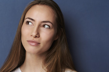 Naklejka premium Thoughtful young woman in blue studio