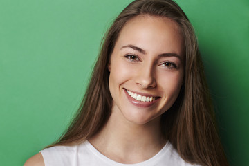 Young smiling brunette against green background