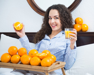 Obraz premium Young woman with orange juice and fruits