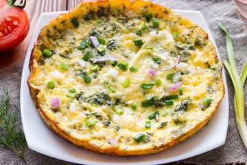 white plate with a delicious omelette on a napkin next to vegetables
