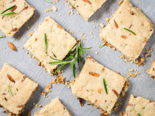 Cookies with rosemary, pignoli and pistachio nuts on baking parchment decorated with rosemary sprigs