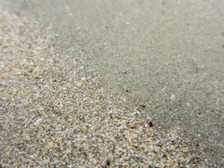 The close-up of sand beach. A smooth surface sand is on the right top and broken seashells sand is on the left below.