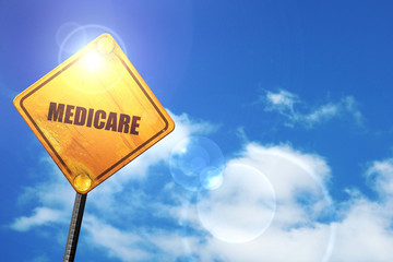 Yellow road sign with a blue sky and white clouds: medicare - obrazy, fototapety, plakaty