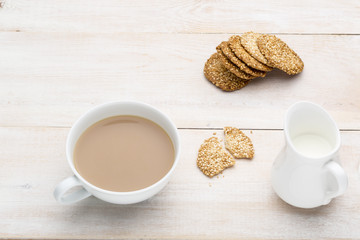 Cup of tea with milk and sesame cookies