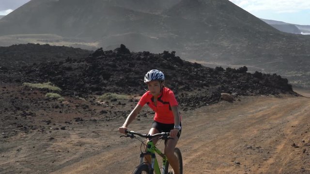Mountain biking MTB cyclist woman cycling on bike trail path. Female mountain biker on bike in sportswear riding bicycle enjoying healthy active lifestyle in nature, Lanzarote, Canary Islands, Spain
