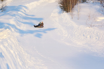 The man with the little boy riding a snow tubing  from the snow
