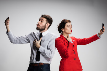Business concept. The two young colleagues holding mobile phones on gray background
