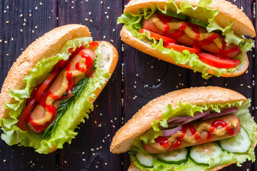 hot dogs of different tastes on a black background with sesame seeds