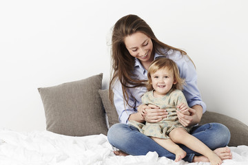 Smiling girl with her mother on bed