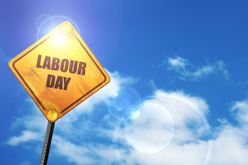 Yellow road sign with a blue sky and white clouds: labour day