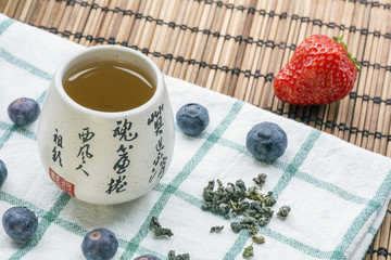 Cup of tea on the white towel with tea and blueberries