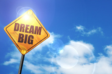 Yellow road sign with a blue sky and white clouds: dream big
