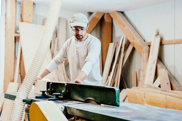 Fototapeta na wymiar Carpenter in a woodworking factory using machinery with no protection gear