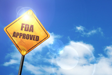 Yellow road sign with a blue sky and white clouds: FDA approved 
