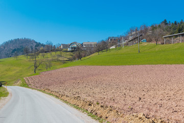 Road passing by typical mountain villages of Slovenia with green meadows.