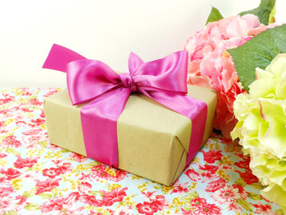 gift box wrapped in recycled paper and bow on printed fabric