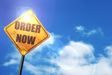Yellow road sign with a blue sky and white clouds: Order now sig