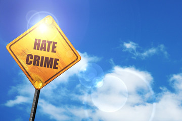 Yellow road sign with a blue sky and white clouds: Hate crime ba