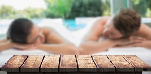 Composite image of couple lying on massage table at spa center