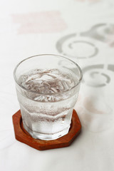 Glass of iced water on wooden coaster